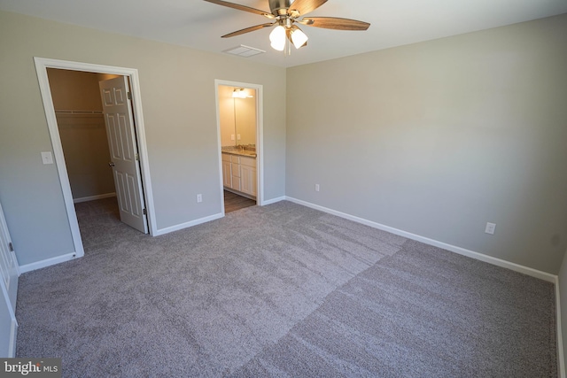 unfurnished bedroom featuring a walk in closet, ceiling fan, a closet, and carpet flooring