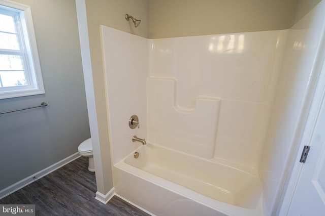 bathroom with shower / washtub combination, wood-type flooring, and toilet