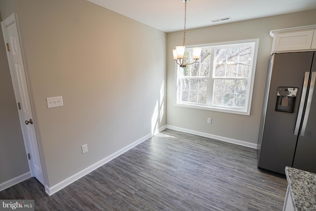 unfurnished dining area featuring a notable chandelier and dark hardwood / wood-style flooring