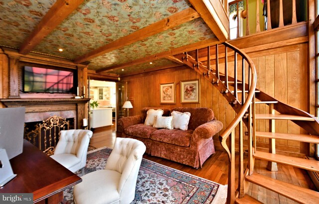 living room with wood walls, dark wood-type flooring, beamed ceiling, and a premium fireplace