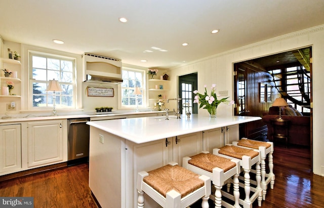 kitchen featuring a breakfast bar area, a kitchen island with sink, dark wood-type flooring, and a healthy amount of sunlight