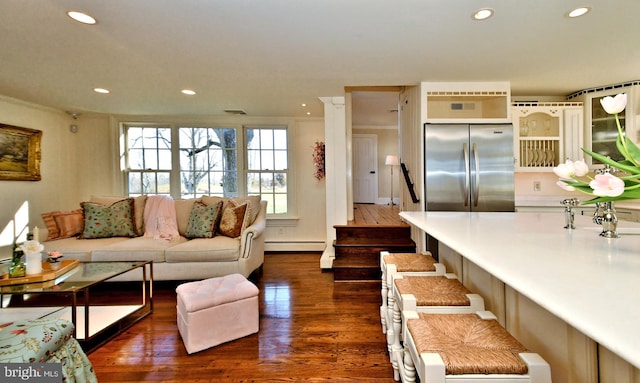 living room featuring a baseboard heating unit, dark wood-type flooring, and sink