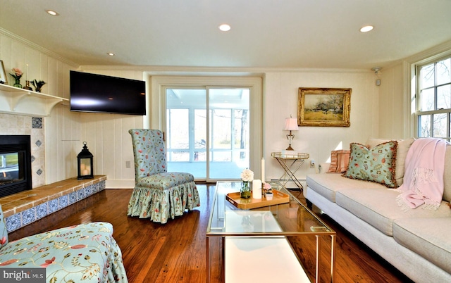 living room with dark hardwood / wood-style floors, crown molding, a tiled fireplace, and a baseboard radiator