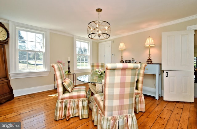 dining space with crown molding, a chandelier, and light hardwood / wood-style floors