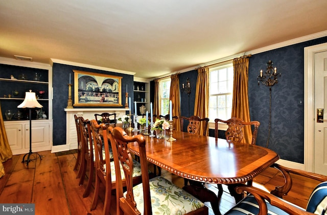 dining space with built in shelves, ornamental molding, and dark wood-type flooring