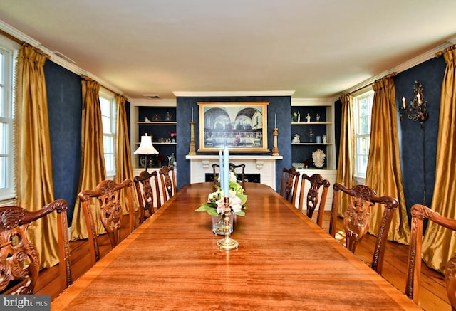 dining space with ornamental molding, built in shelves, and wood-type flooring