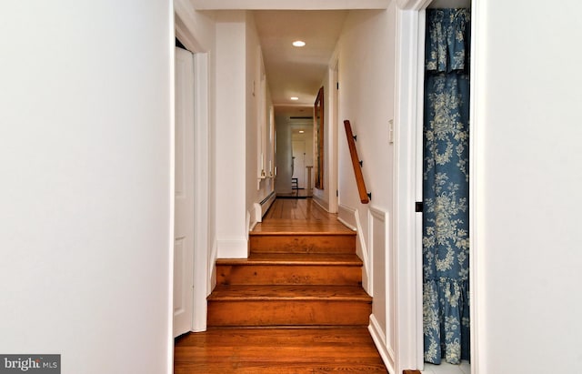 stairs featuring baseboard heating and dark wood-type flooring