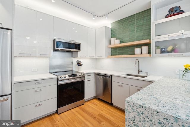 kitchen featuring rail lighting, light hardwood / wood-style flooring, white cabinetry, appliances with stainless steel finishes, and sink