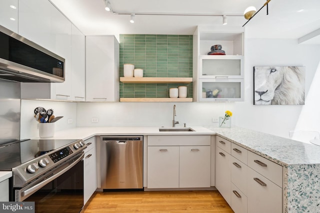 kitchen featuring white cabinets, appliances with stainless steel finishes, sink, and light wood-type flooring