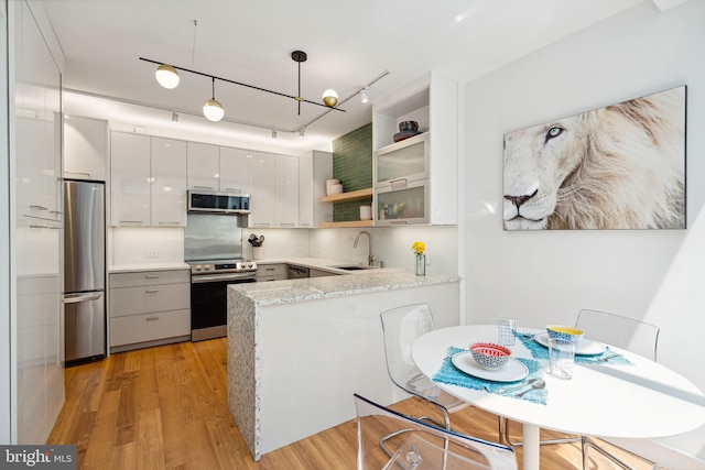 kitchen with kitchen peninsula, appliances with stainless steel finishes, sink, light wood-type flooring, and gray cabinets