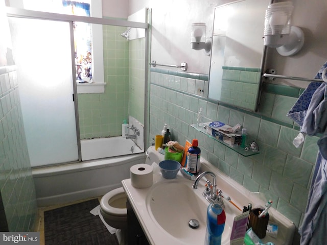 full bathroom featuring tile walls, sink, toilet, tasteful backsplash, and enclosed tub / shower combo