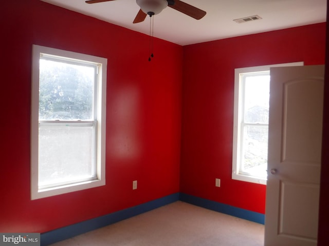 carpeted spare room featuring plenty of natural light and ceiling fan