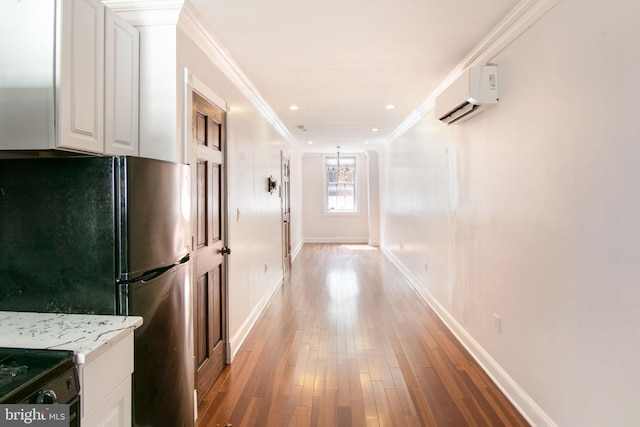 corridor featuring a wall mounted air conditioner, crown molding, and light wood-type flooring