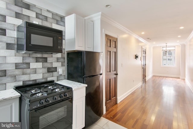 kitchen with light stone counters, white cabinets, black appliances, and light wood-type flooring