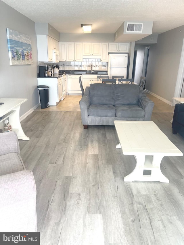 living room with light hardwood / wood-style floors, sink, and a textured ceiling