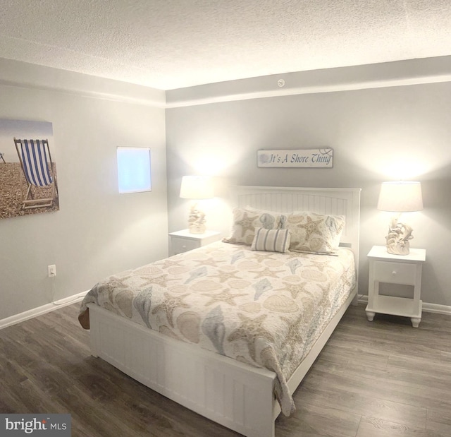 bedroom with a textured ceiling and dark hardwood / wood-style flooring