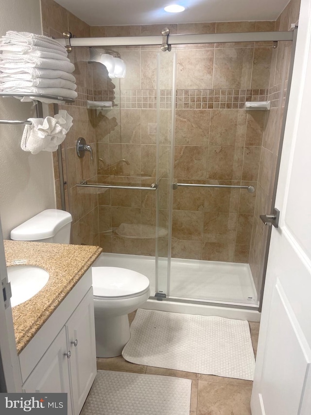 bathroom featuring walk in shower, vanity, tile patterned flooring, and toilet