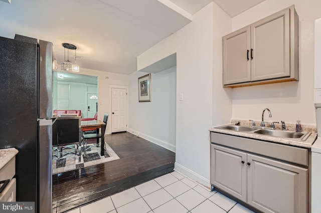 kitchen with pendant lighting, light countertops, gray cabinetry, freestanding refrigerator, and a sink