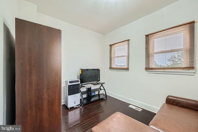 office space with dark wood-style flooring, visible vents, baseboards, and heating unit