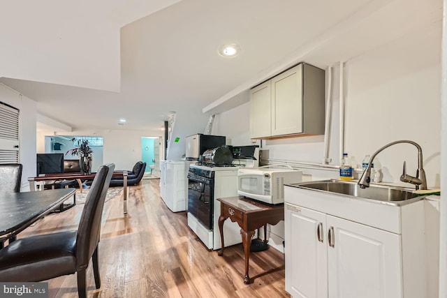 kitchen with light countertops, white appliances, a sink, and light wood-style flooring