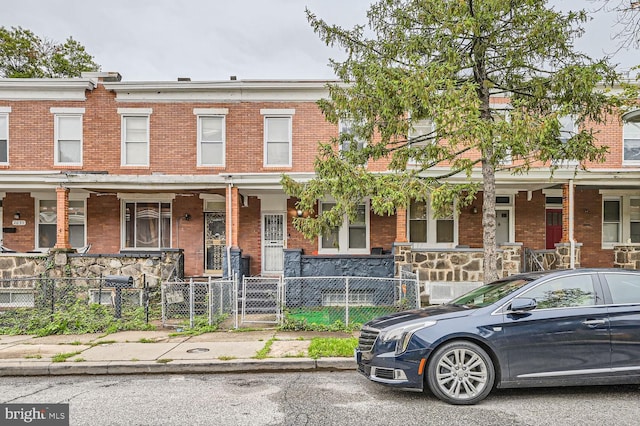 townhome / multi-family property with a fenced front yard and brick siding