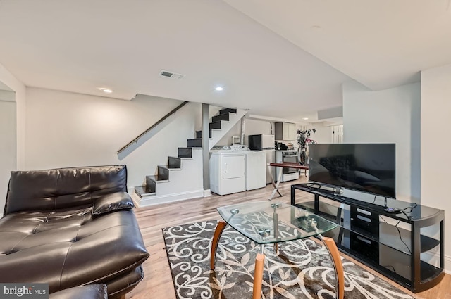 living room featuring recessed lighting, visible vents, stairway, light wood-style floors, and washing machine and dryer