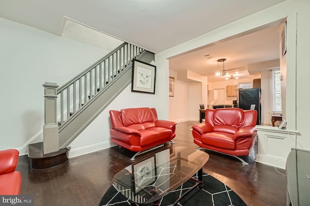 living area featuring stairs, baseboards, and dark wood-style flooring