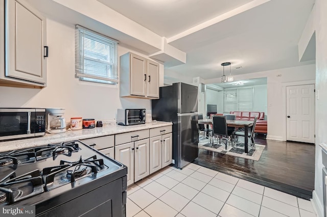 kitchen with light tile patterned floors, a toaster, visible vents, decorative light fixtures, and stainless steel appliances