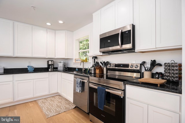 kitchen with stainless steel appliances, sink, white cabinets, and light wood-type flooring