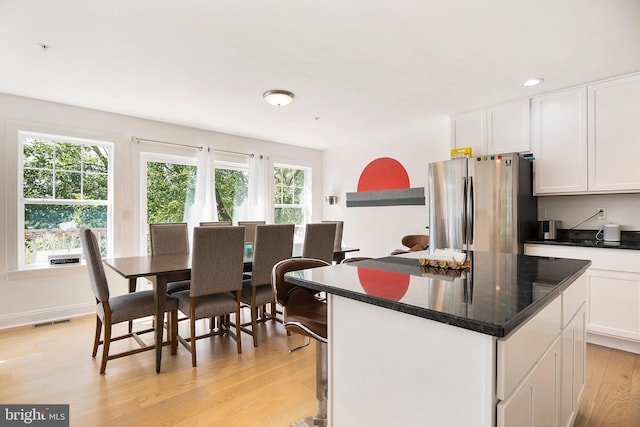 kitchen featuring a center island, white cabinets, stainless steel refrigerator, and light wood-type flooring