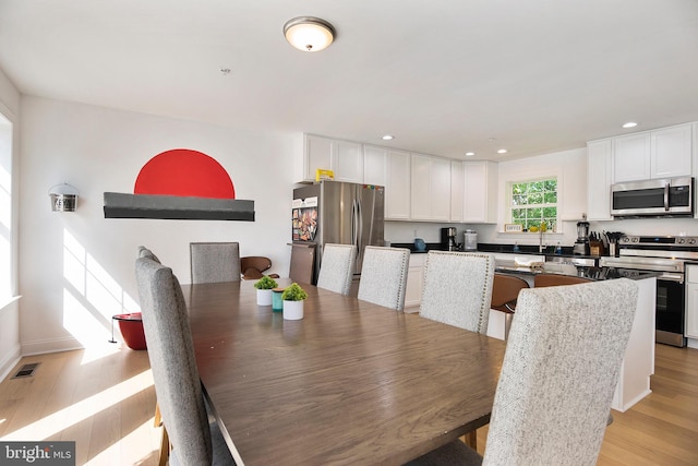 dining space with light hardwood / wood-style floors and sink