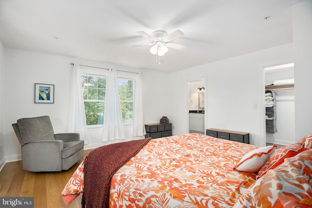 bedroom featuring ensuite bath, a closet, light wood-type flooring, ceiling fan, and a walk in closet