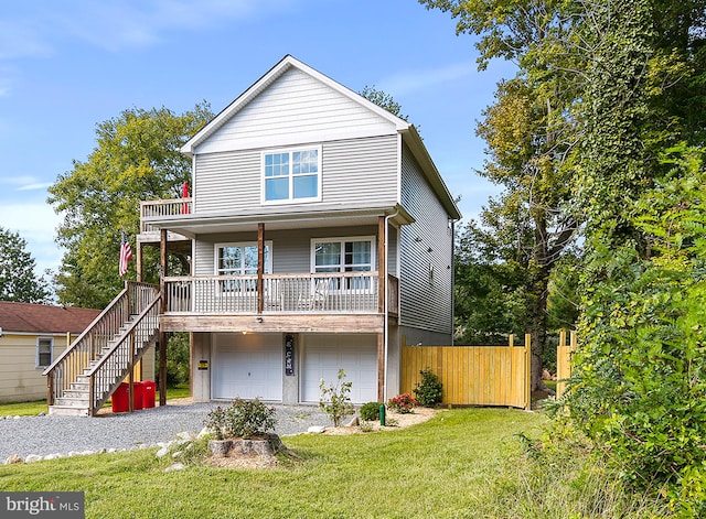 view of front of home with covered porch, a front yard, and a garage