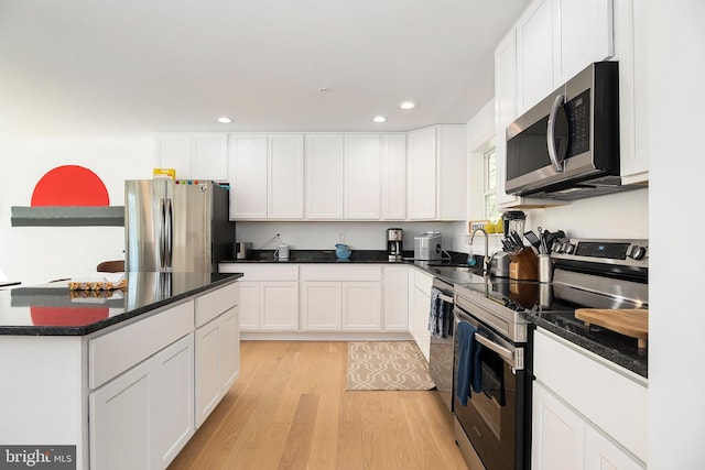 kitchen with white cabinets, light hardwood / wood-style floors, and appliances with stainless steel finishes