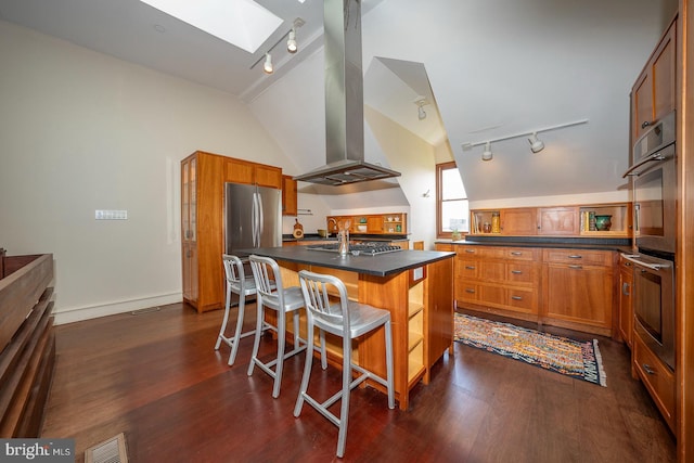 kitchen with a skylight, dark hardwood / wood-style floors, extractor fan, rail lighting, and a breakfast bar