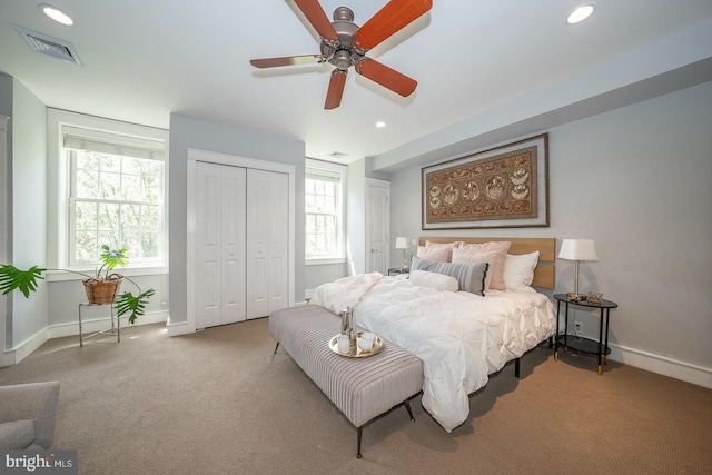 carpeted bedroom featuring a closet, multiple windows, and ceiling fan