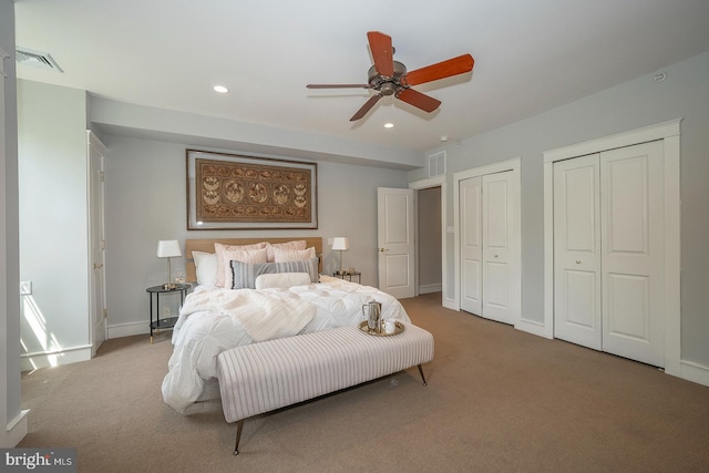 carpeted bedroom with ceiling fan and two closets