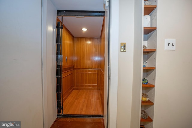 hallway with elevator and hardwood / wood-style flooring