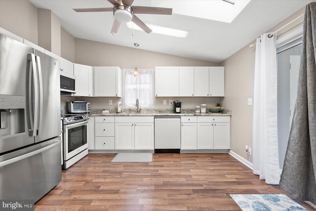 kitchen with vaulted ceiling with skylight, stainless steel fridge, ceiling fan, stove, and dishwashing machine