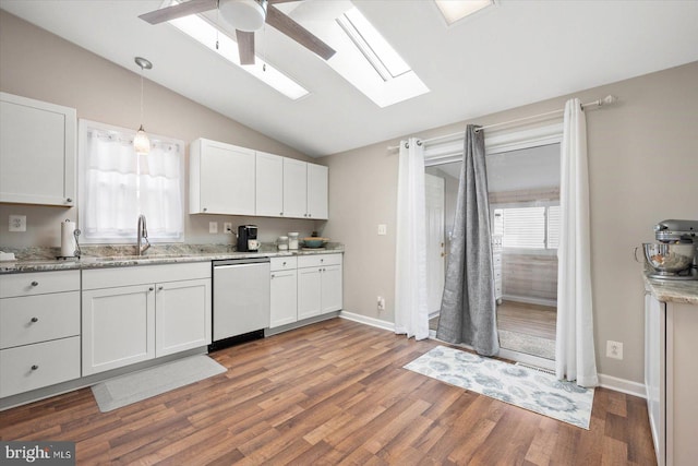 kitchen featuring a healthy amount of sunlight, dishwashing machine, vaulted ceiling with skylight, and ceiling fan