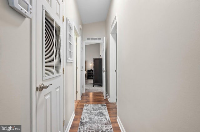 hallway with vaulted ceiling and dark hardwood / wood-style floors