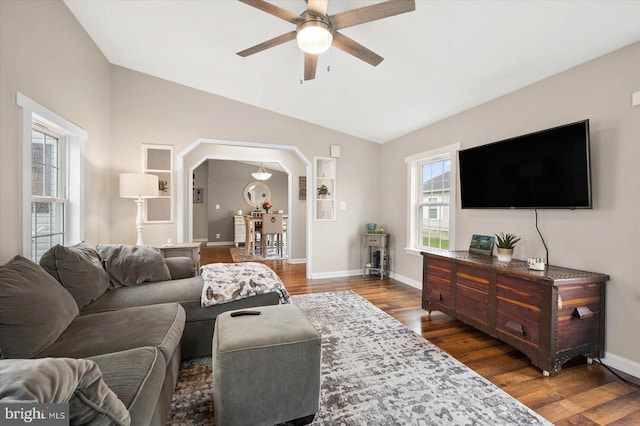 living room with ceiling fan, vaulted ceiling, and dark wood-type flooring