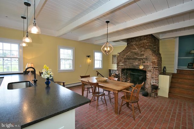 dining space featuring beam ceiling, sink, a brick fireplace, an inviting chandelier, and a baseboard radiator