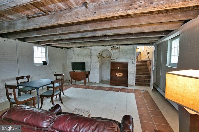 tiled living room featuring baseboard heating and brick wall