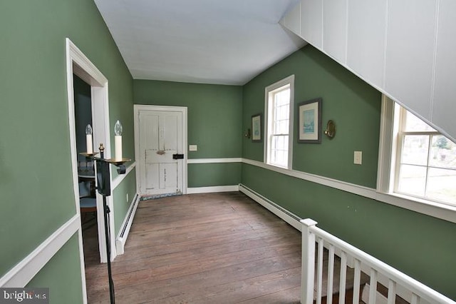 interior space featuring wood-type flooring, baseboard heating, and a wealth of natural light