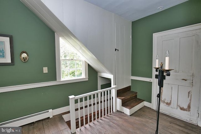 stairs featuring a baseboard heating unit and hardwood / wood-style flooring