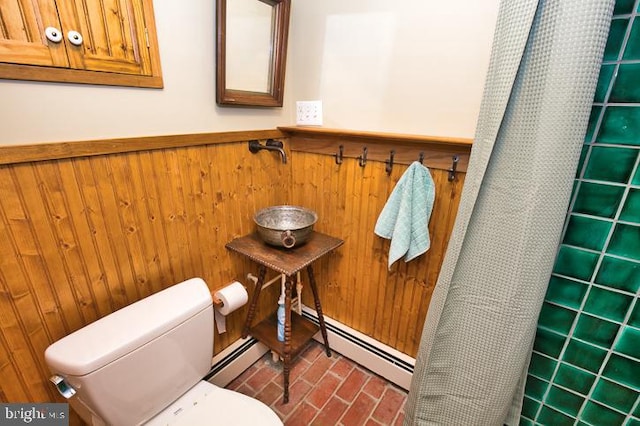 bathroom with baseboard heating, wooden walls, toilet, and walk in shower