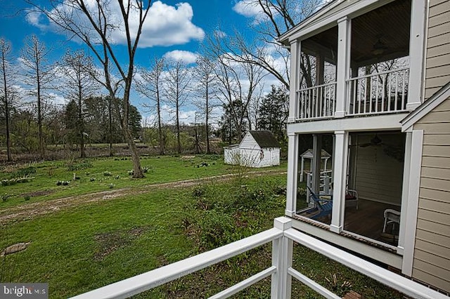 view of yard featuring a sunroom, ceiling fan, and a balcony