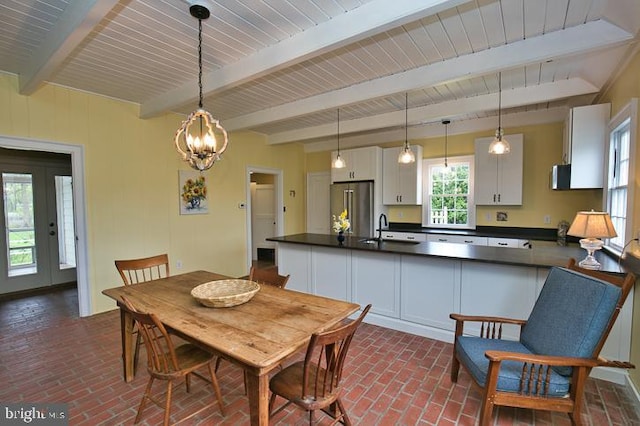 dining room featuring beam ceiling, sink, a chandelier, and a wealth of natural light