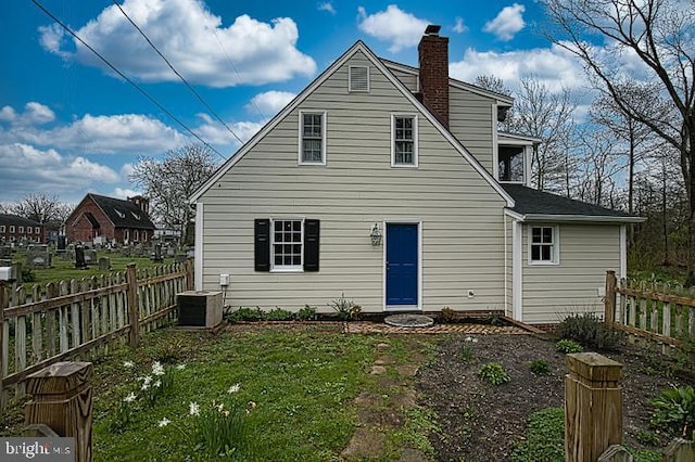 rear view of house featuring central AC and a yard